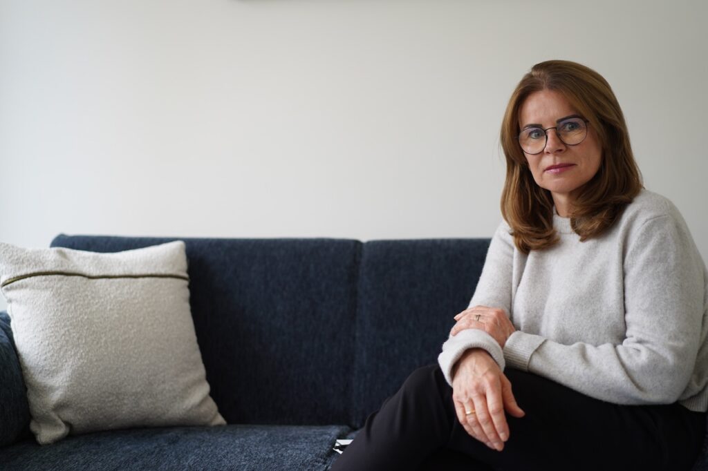 Emotionale Verletzlichkeit Ursachen: Frau sitzt ruhig auf einem Sofa und wirkt offen, aber sensibel.